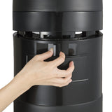 A close-up of a hand pressing a latch on a large, black beverage dispenser with an insulated stainless steel vacuum liner, likely to open or detach a section. The plain background keeps the focus on the hand and latch mechanism.
