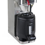 A commercial stainless steel coffee maker with a black insulated beverage dispenser beneath the brew spout. The dispenser features a transparent window to show liquid levels, a carrying handle, and a bottom spout for easy coffee dispensing.