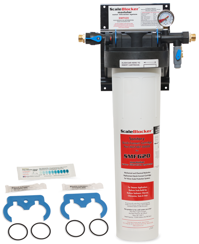 A Vulcan SMF620 SCALEBLOCKER Water Treatment System is mounted on the wall. Below, replacement parts include two blue wrenches, two black O-rings, and two small packets. The white filter housing features a pressure gauge and product labeling.
