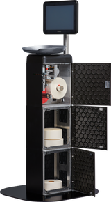 Freestanding black Hobart FS-100 self-service kiosk with open cabinet doors showing rolls of labels inside, a touchscreen monitor on top, a weighing tray, and exposed internal mechanisms for printing and dispensing labels.