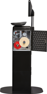 A standing black Hobart FS-100 Self-Serve Scale kiosk features a touchscreen on top and an open front panel revealing internal components, including a red and beige ribbon roll, wiring, and a mesh-covered side door. The kiosk sits on a round base.