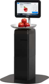 A digital self-checkout kiosk with a Hobart FS-200 touchscreen scale displays apples on a tray. The screen shows product info, Organic Red Delicious Apples, weight, price, and keypad with four red apples sitting atop the black kiosk.