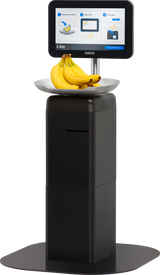 A self-service checkout kiosk features a touchscreen scale with weighing instructions and an image of bananas. A bunch of bananas sits on the silver platform beneath the display. The black Hobart FS-200 stands on a flat base.