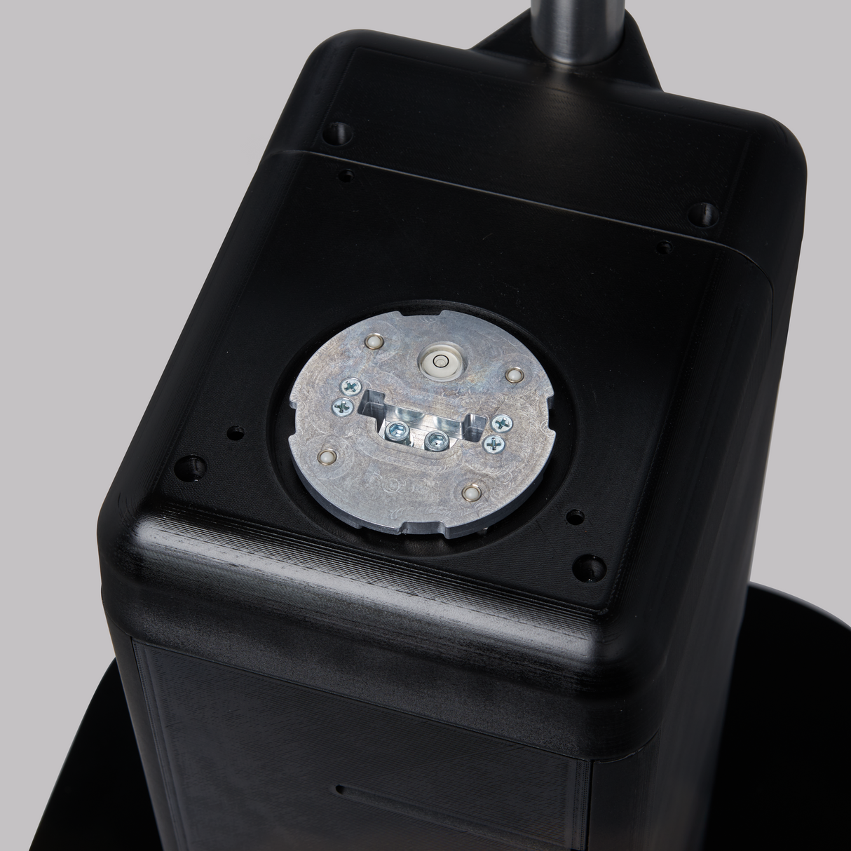 A close-up view of a Hobart FS-10V FreshServe Self-Serve Scale shows a black rectangular electronic device with a circular metallic plate on top, secured by several screws. The background is plain gray, with part of a silver pole visible at the top.