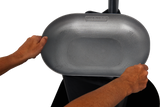 Two hands hold a large, oval, gray metal pan labeled HOBART above a free-standing touchscreen scale. The plain white background highlights the pan and the hands positioning it on the device.