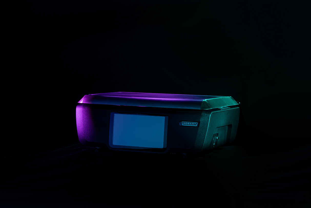 A flatbed scanner is shown against a dark background, illuminated by soft purple and teal lighting. The scanner’s lid and front panel are visible, featuring a blank customer display and the brand label “LOSART” on its side.