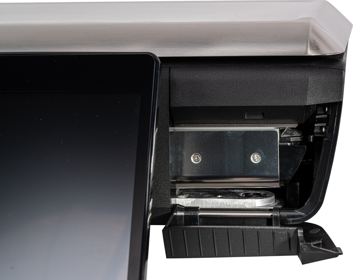 A close-up of a GTS Printer point-of-sale terminal shows the edge of a touchscreen on the left and the receipt paper compartment with a metal holder and partially exposed roll inside on the right. The plastic cover is lifted, revealing internal parts.