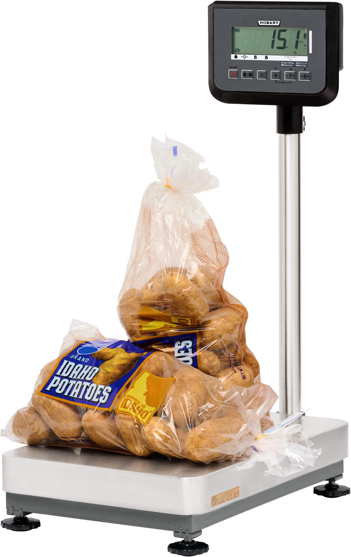A plastic bag of Idaho potatoes sits on a legal for trade bench receiving scale with a 300 lb capacity. The display reads 15.14 pounds, and the partially open bag reveals several brown potatoes against a plain white background.