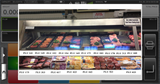 A meat counter displays various raw steaks, chops, and cuts arranged on trays with PLU numbers. Packaged meats are on the lower shelf. A Hobart HTI-7LH4 scale/printer with a 7 customer display is visible among the store signage.