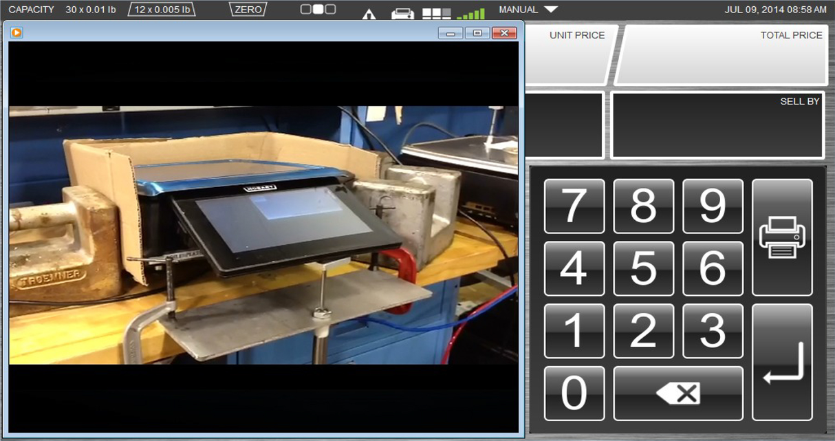 A digital touchscreen scale display, possibly a 7 customer display, is shown on the left atop a metal stand and wooden surface. On the right, an HTi scale printer interface shows NUMERIC KEYPAD, UNIT PRICE, TOTAL PRICE, SELL BY buttons; date reads JUL 09, 2014.