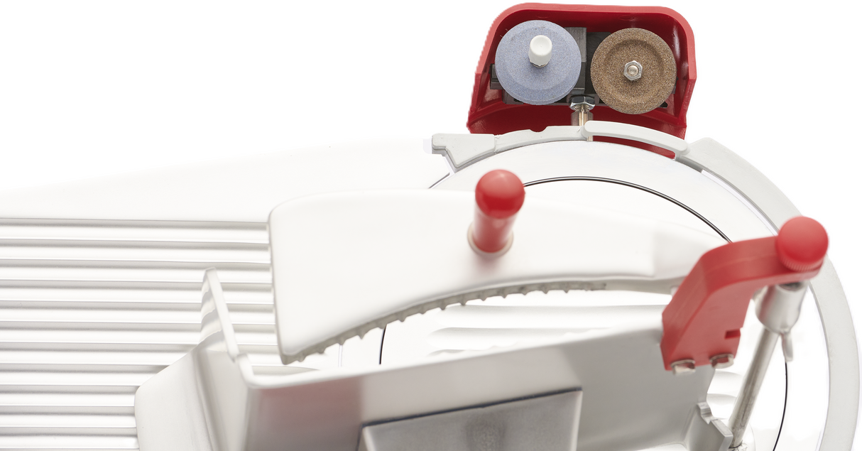 Close-up of a Berkel B10-SLC gravity feed slicer focusing on the blade area, with a white body, red handle, and sharpening tools at the top. The image highlights its industrial design and key operational parts.