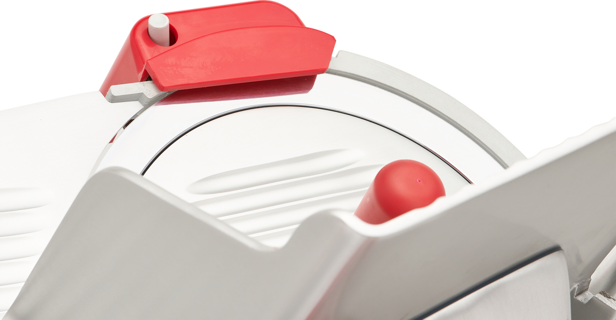 Close-up of a manual slicer with a sharp carbon steel knife, a white ridged platform, and a red safety guard handle. The sleek, modern Berkel B12-SLC design highlights the slicing mechanism and protective red components.