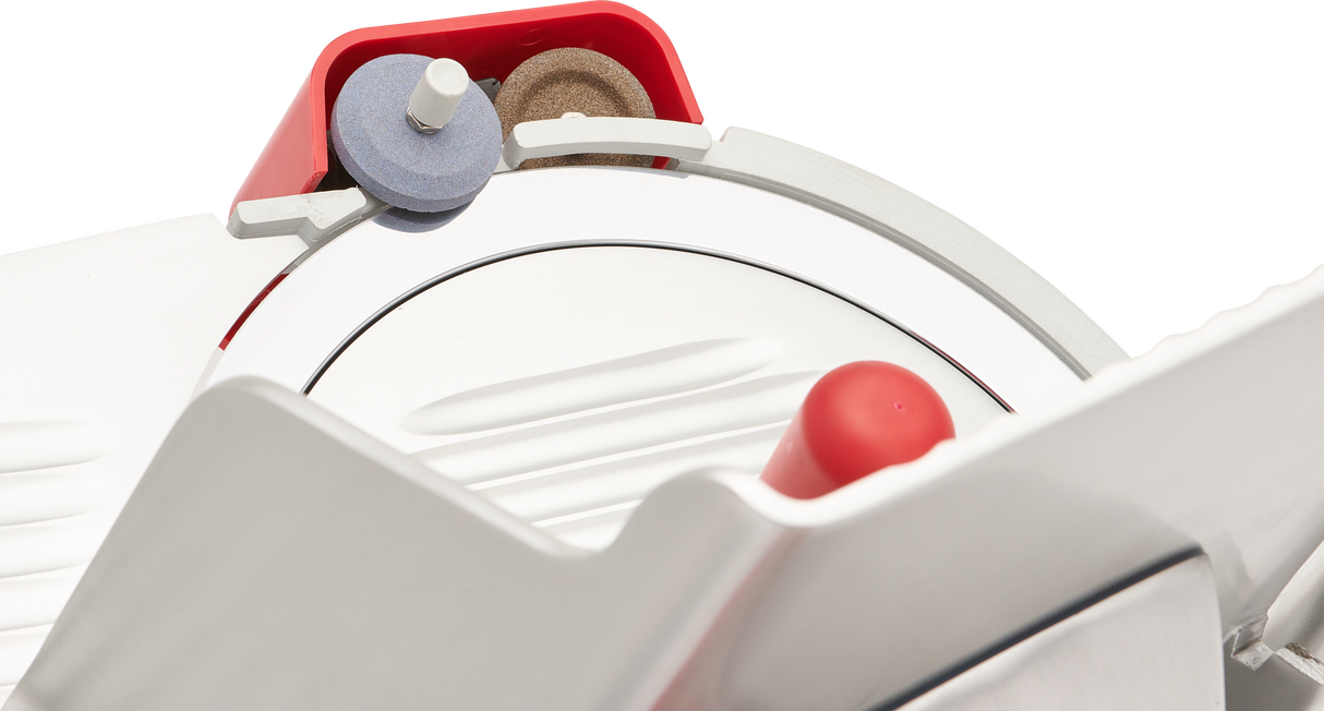 Close-up of a Berkel slicer’s 12 inch carbon steel knife with a red guard, blue and brown sharpening stone, and red handle. Clean, modern materials stand out against the black background, highlighting this manual gravity feed slicer’s design.