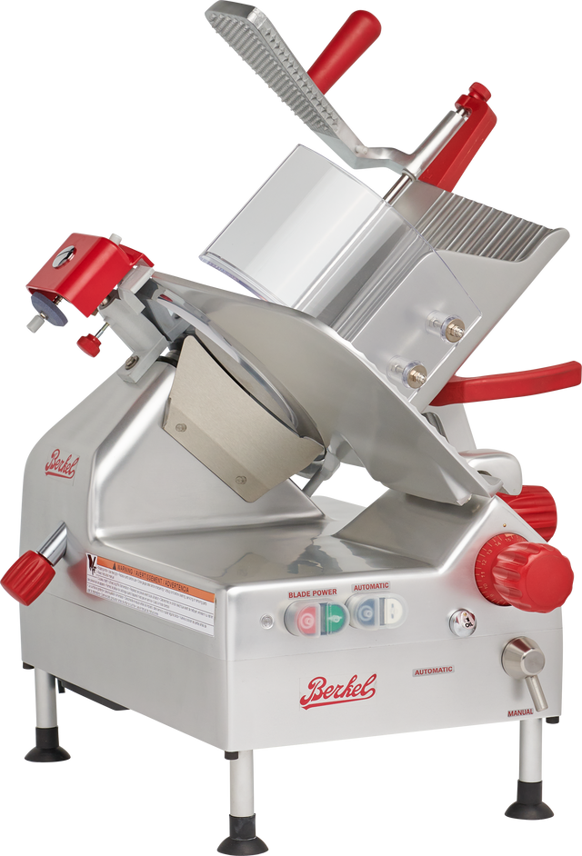 A silver and red Berkel gravity feed slicer with a 12 carbon steel knife, tilted blade, food carriage, safety guard, control knobs, and labeled buttons. The machine stands on four rubber-tipped feet and displays the Berkel logo on its side and front.