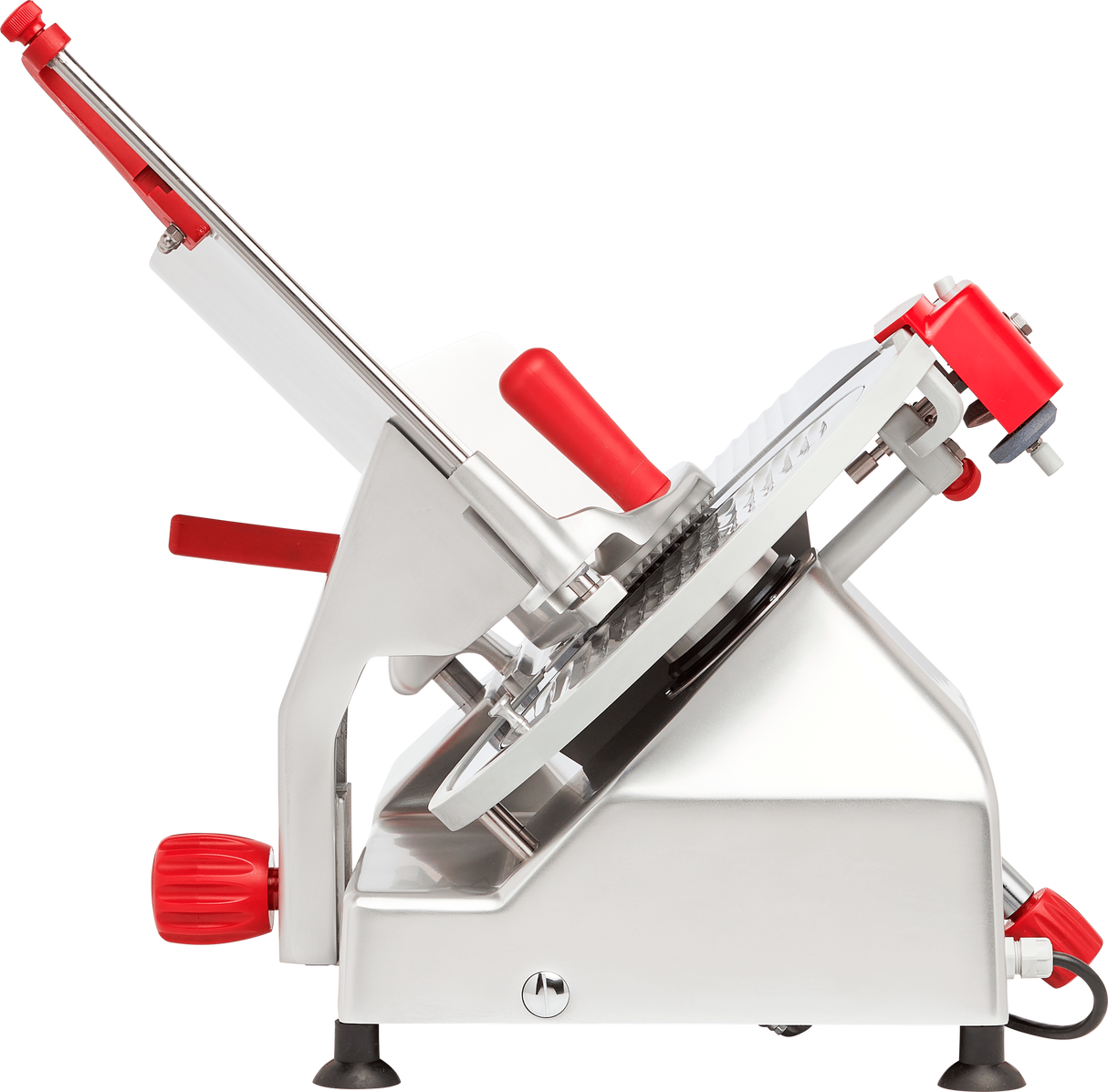 A commercial manual gravity feed slicer with a shiny silver body and bright red handles is shown side-on. It features a circular serrated carbon steel knife and an adjustable angled tray for smooth sliding and slicing of food items.