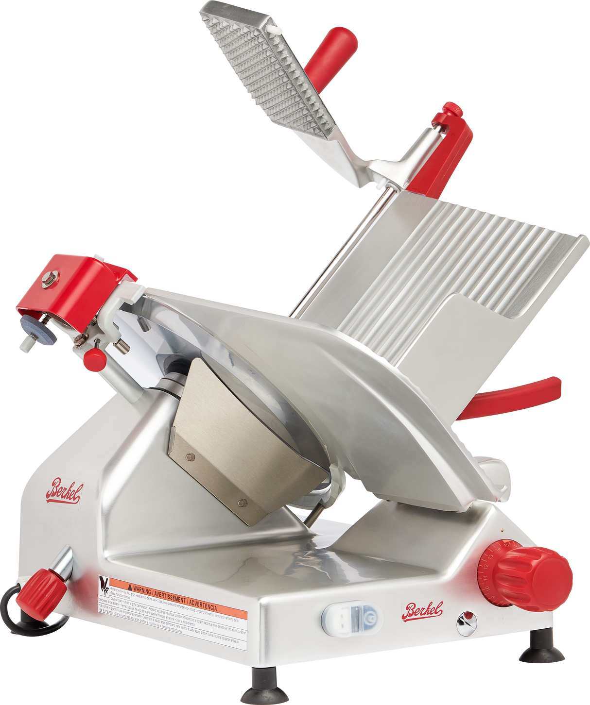 A manual gravity feed slicer with a tilted stainless steel platform, carbon steel knife, large circular blade, red handles, and adjustment knobs. Designed for slicing deli meats and cheeses, it features safety guards and front control switches.
