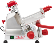 A stainless steel Berkel gravity feed slicer with red knobs and handles, a tilted adjustable platform, and a sharp circular blade. The machine has an on/off switch and the Berkel logo in red. Its overall design is modern and industrial.