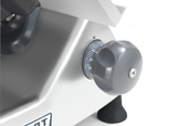 Close-up of a gray adjustment knob with numbered markings on a Heavy Duty Meat Slicer, likely the Hobart HS6N-1R. The ribbed knob shows numbers from 0 to 15. Below, a rubber foot and part of a logo are visible.