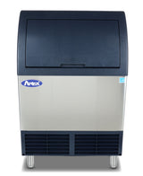 A commercial cube-style ice machine with a stainless steel body, black front panel, and bottom vent. The flip-up door accesses the stainless steel ice bin, while four metal legs support the unit. A blue brand logo sits on the upper left.