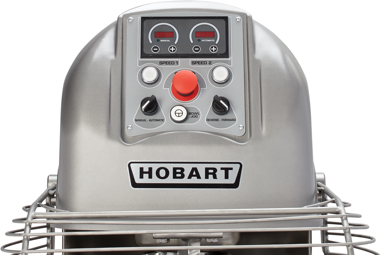Close-up of a Hobart Spiral Mixer control panel, featuring two speed dials, a large red emergency stop button, manual and automatic controls, and a metal safety guard. The 130-pound capacity Hobart brand name is prominently displayed.