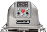 Close-up of a Hobart Spiral Mixer control panel, featuring two speed dials, a large red emergency stop button, manual and automatic controls, and a metal safety guard. The 130-pound capacity Hobart brand name is prominently displayed.