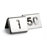 Two metallic table number signs from the TableCraft number tent set are displayed. The front sign shows a cut-out number 1, and the one behind shows 50. Both are folded into tent shapes and made of brushed stainless steel.
