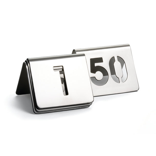 Two metallic table number signs from the TableCraft number tent set are displayed. The front sign shows a cut-out number 1, and the one behind shows 50. Both are folded into tent shapes and made of brushed stainless steel.