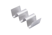 The Taco Taxi Server is a stainless steel holder with a wavy zigzag design, featuring three curved slots that holds 2-3 tacos upright. A plain white background highlights its metallic finish and sleek, modern look.