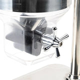 Close-up of a shiny metal cereal dispenser with a transparent container and a chrome paddle handle. The handle is attached to a spout, ideal for dispensing dry food or coffee. The clean, modern design suggests it’s likely a TableCraft product.