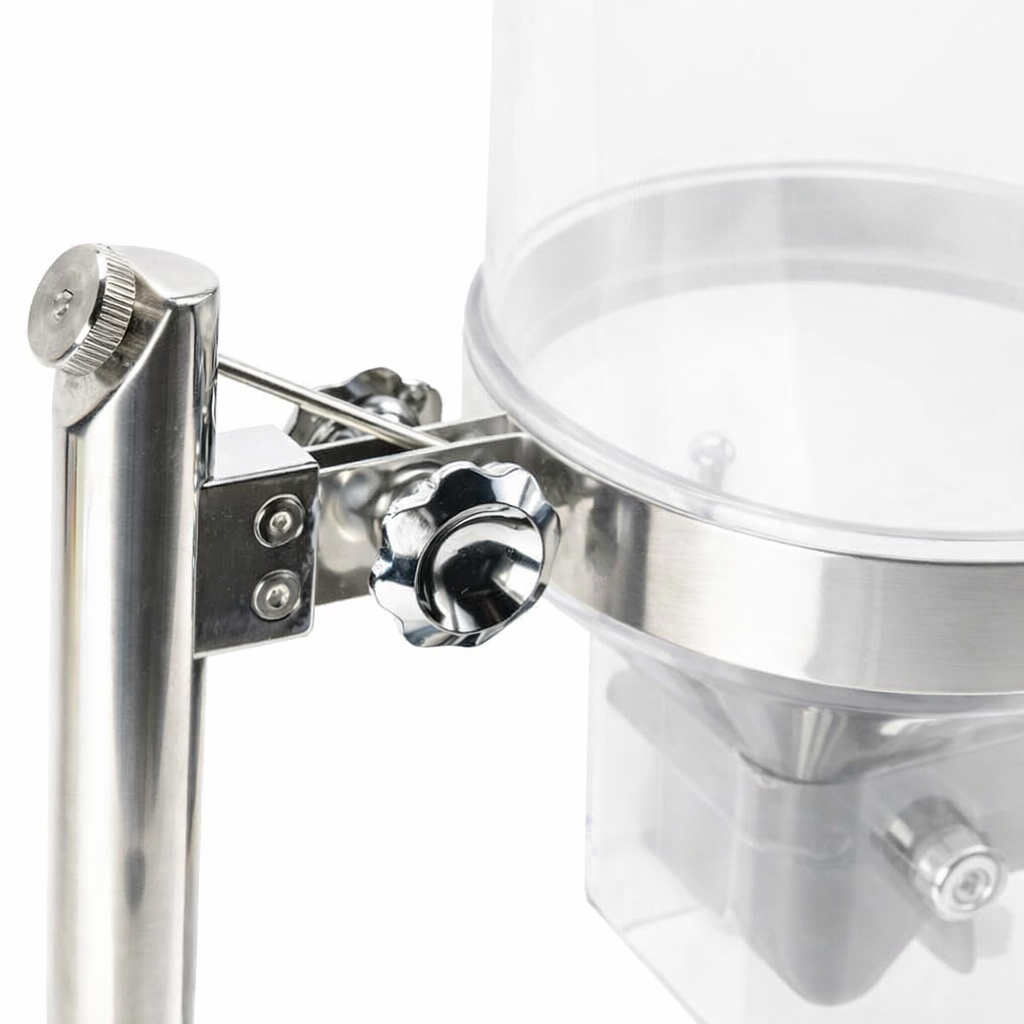 Close-up of a TableCraft cereal dispenser with a shiny black adjustment knob and bracket securing it to a stainless steel pole. The clear cylindrical container above is paired with a paddle handle for easy dispensing.
