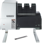 A Hobart 403-13 commercial knife sharpener with a silver and black finish stands on metal legs. An ON/OFF switch, warning label, and voltage specification are visible. A metal cleaning tool with several prongs rests in front.