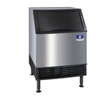 A commercial undercounter ice maker with a stainless steel body, black vented front panel, and black lid. Featuring four adjustable legs and a blue Manitowoc NEO logo with a white snowflake, the air-cooled ice makers control panel sits on the top right corner.