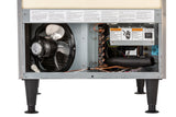 Close-up of the lower section of an undercounter ice maker with its service panel removed, revealing a fan, copper coils, wires, warning labels, a control box, and black insulation tubing—all supported by four black legs.
