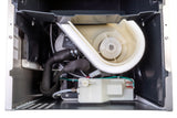 Inside view of an ADA Compliant undercounter ice maker showing internal components: a white plastic water reservoir with wires, black hoses, a fan-like impeller, and various metal and plastic parts inside a metal housing, illustrating the water and cooling system.