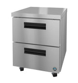 A Hoshizaki undercounter freezer features two spacious stainless steel drawers, black recessed handles, and four small caster wheels. The appliance boasts a smooth, modern finish and a certification sticker on the bottom right corner.