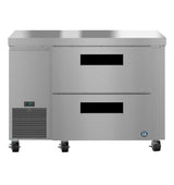 A Hoshizaki stainless steel undercounter refrigerator with two front drawers, a ventilation grate, digital display on the lower left, four caster wheels, and a blue logo near the bottom right corner.
