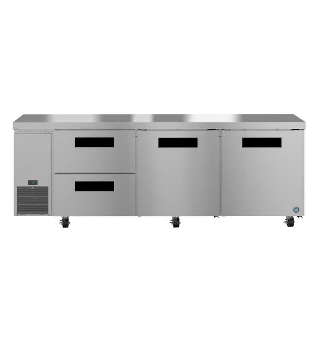 A commercial undercounter refrigerator featuring two pull-out drawers on the left, two large reach-in swing doors on the right, a ventilation grate below, and four caster wheels for mobility. Its sleek, stainless steel design is both practical and industrial.