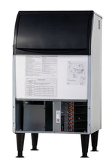 A commercial undercounter ice maker with a black top and white body is shown on black legs. The front panel is open, revealing technical instructions, a diagram, and internal components like copper coils and wiring. The unit stands on a white background.