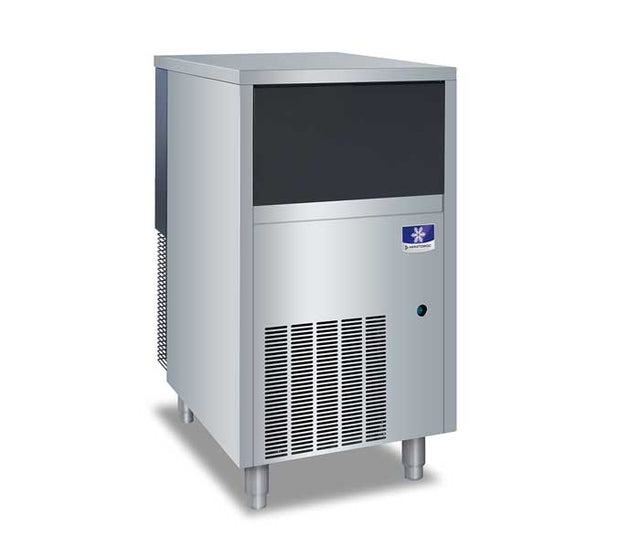 A commercial Manitowoc ice maker stands on four legs with a sleek, industrial design. The upper section has a black panel, while the lower portion features a vented grille and a small blue logo near the top right.
