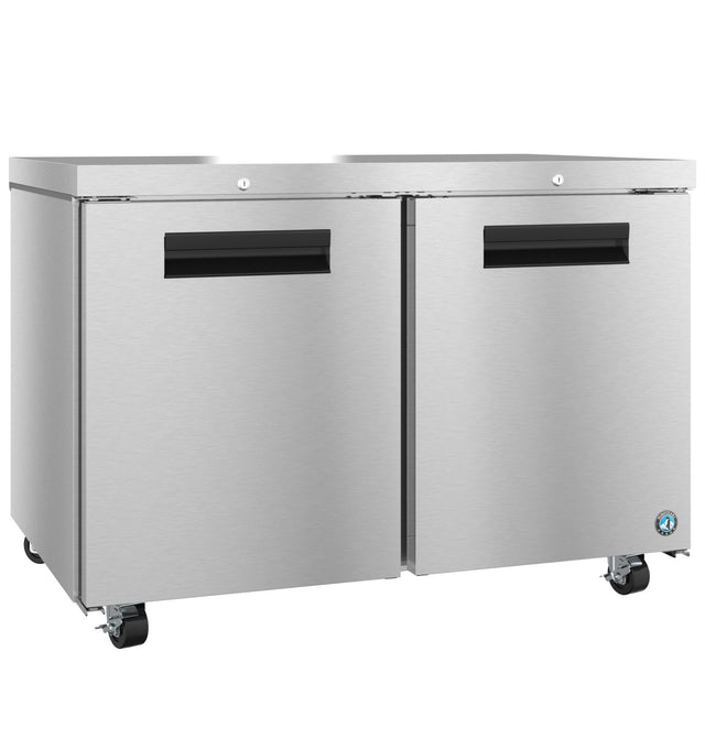 A Hoshizaki Steelheart Series undercounter refrigerator with two front doors, black handles, and four caster wheels for mobility. The smooth, reflective stainless steel surface features a small blue logo on the lower right corner.