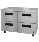 A Hoshizaki stainless steel undercounter refrigerator unit with four pull-out drawers, black recessed handles, and small wheels for mobility. The flat, smooth top and round blue certification sticker complete its sleek, functional design.