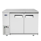 A silver commercial under-counter refrigerator, such as the Atosa SBB48GRAUS1 Back Bar Cooler, features two doors with black handles and ventilation on the bottom left side. The unit is on small wheels, has indicator lights, and displays a logo in the upper left corner. The surface is flat and stainless steel for a sleek, modern finish.