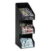 A black, three-tiered condiment organizer sits on the countertop holding mustard, pepper, and sweetener packets. Each compartment is filled and clearly organized for easy access, making it perfect for any kitchen or coffee station.