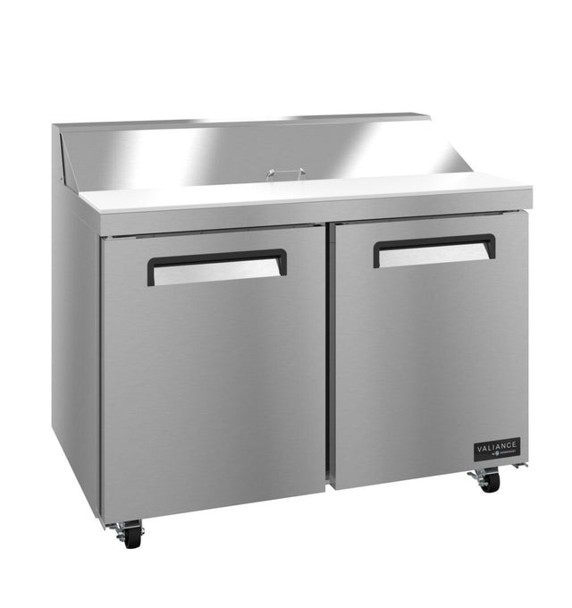 A Valiance Series stainless steel sandwich prep refrigerator with two doors, a flat work surface, raised rear edge, and black handles. The unit sits on four wheels, with the VALIANCE label visible on the lower right corner.