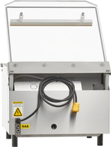 A Berkel stainless steel single chamber Vacuum Packaging Machine with a transparent top lid, a coiled black and yellow power cord, a gas warning label, and a reflective surface; viewed from the front with the lid open to reveal internal components.