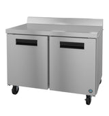 A Hoshizaki commercial stainless steel refrigerator with two doors, black horizontal handles, and four wheels. The unit features a flat top worktop freezer with a raised back edge and a blue circular logo near the bottom right corner. Plain white background.