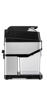 A stainless steel and black countertop ice crusher is shown from the side. It has a clear plastic collection container at the bottom, with a power cord wrapped at the back. The lid at the top is slightly open. The design is modern and compact.