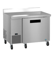 A stainless steel worktop freezer on four caster wheels with a single solid door, a digital control panel on the lower left, and a raised back edge. This ENERGY STAR unit boasts a sleek, modern look and is isolated on a white background.