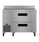 A Hoshizaki stainless steel worktop refrigerator with two black-handled drawers, digital temperature display, ventilation grilles, and four caster wheels. Sleek and reflective, it's designed for professional kitchen use.
