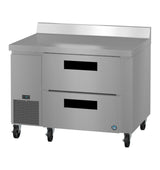 A Hoshizaki stainless steel worktop refrigerator features two drawers, a backsplash, vented cooling on the lower left, digital temperature display, smooth surface, casters for mobility, and a logo on the bottom right corner.